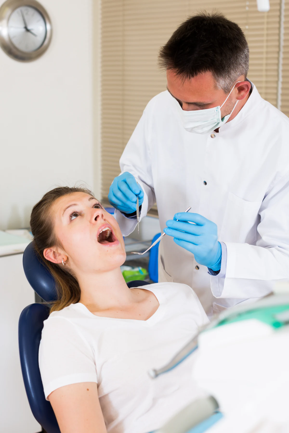 Zahnarzt untersucht eine Patientin im Behandlungsstuhl