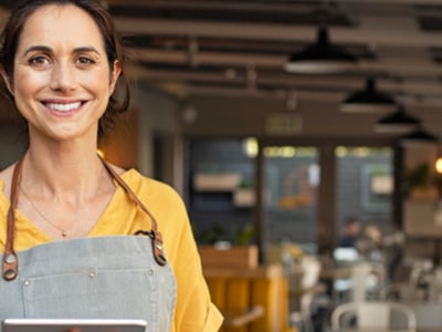Inhaberin eines Cafés hält ein Tablet im Eingangsbereich